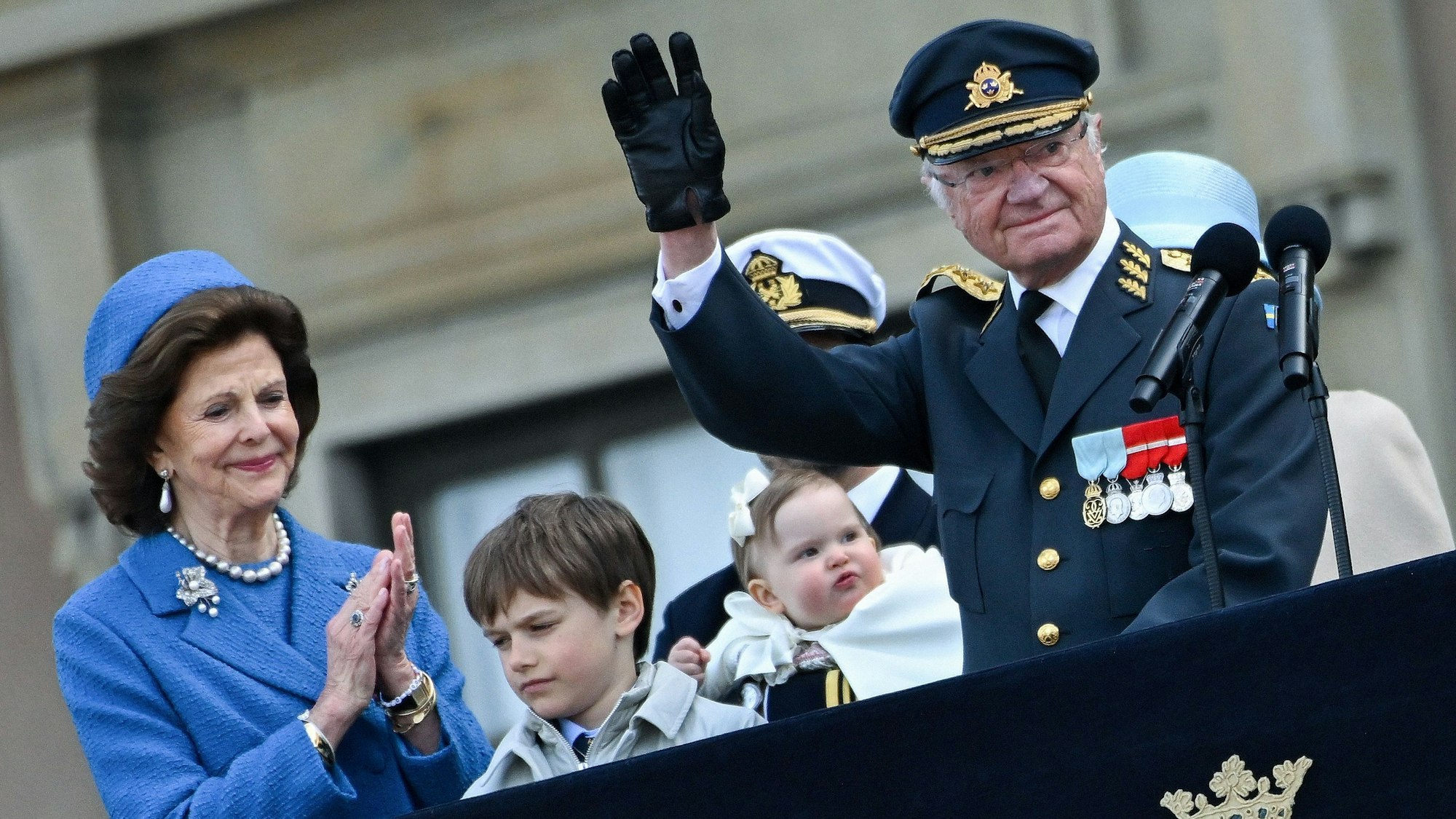 König Carl XVI. Gustaf und Königin Silvia grüßen vom Balkon des Stockholmer Schlosses, flankiert von Prinz Carl Philip mit Prinzessin Ines und Prinz Gabriel.