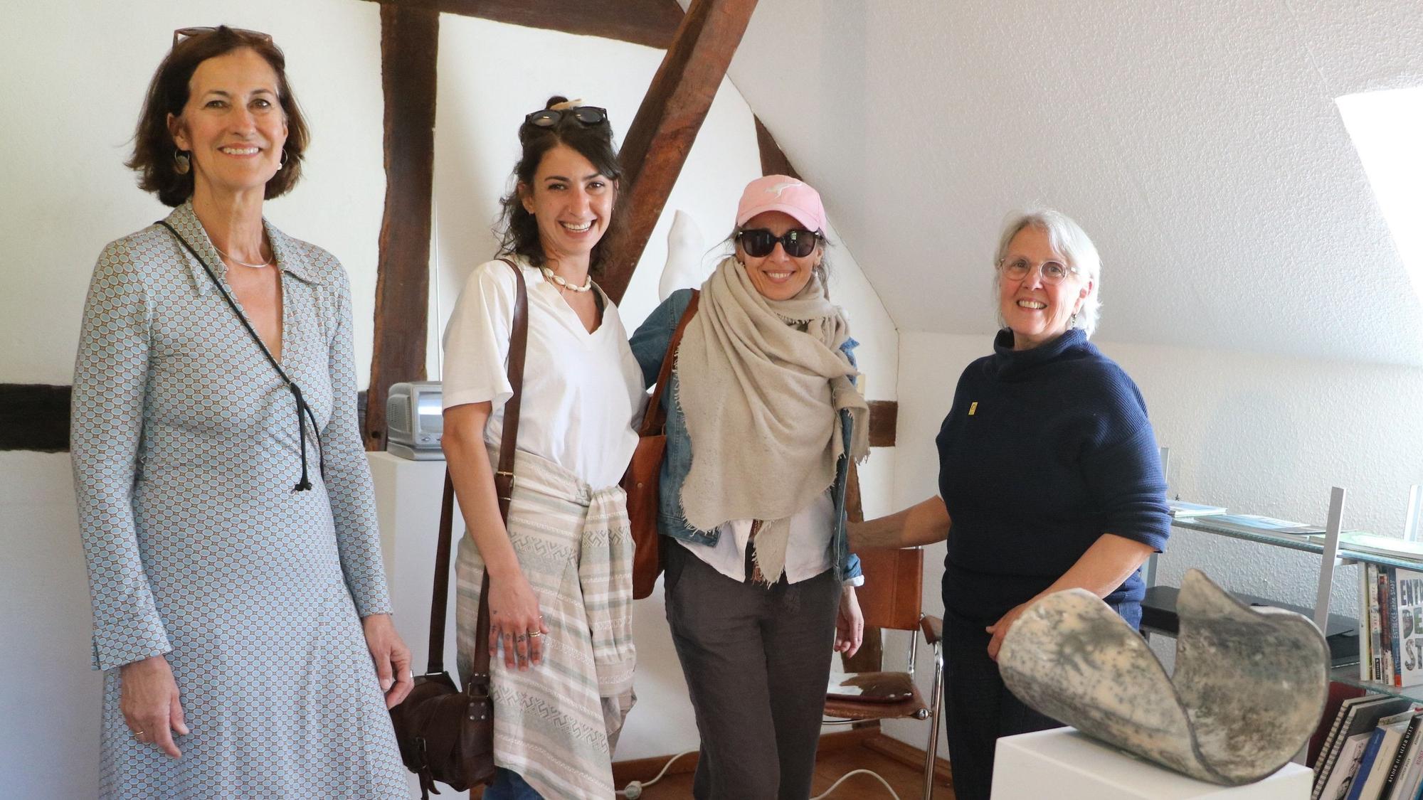 Vier Frauen stehen in einem Fachwerkhaus, neben ihnen Steinskulpturen.
