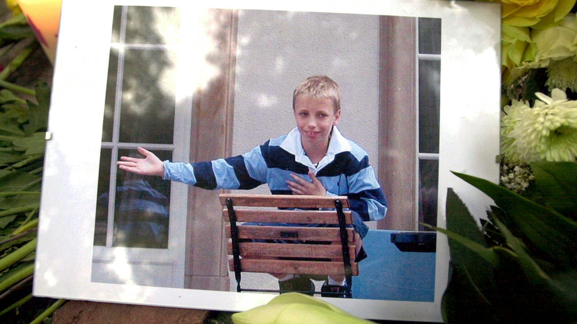 Inmitten von Blumengestecken und Kerzen liegt 2002 vor dem Elternhaus des Mordopfers in Frankfurt am Main ein Bild des ermordeten Jakob von Metzler.