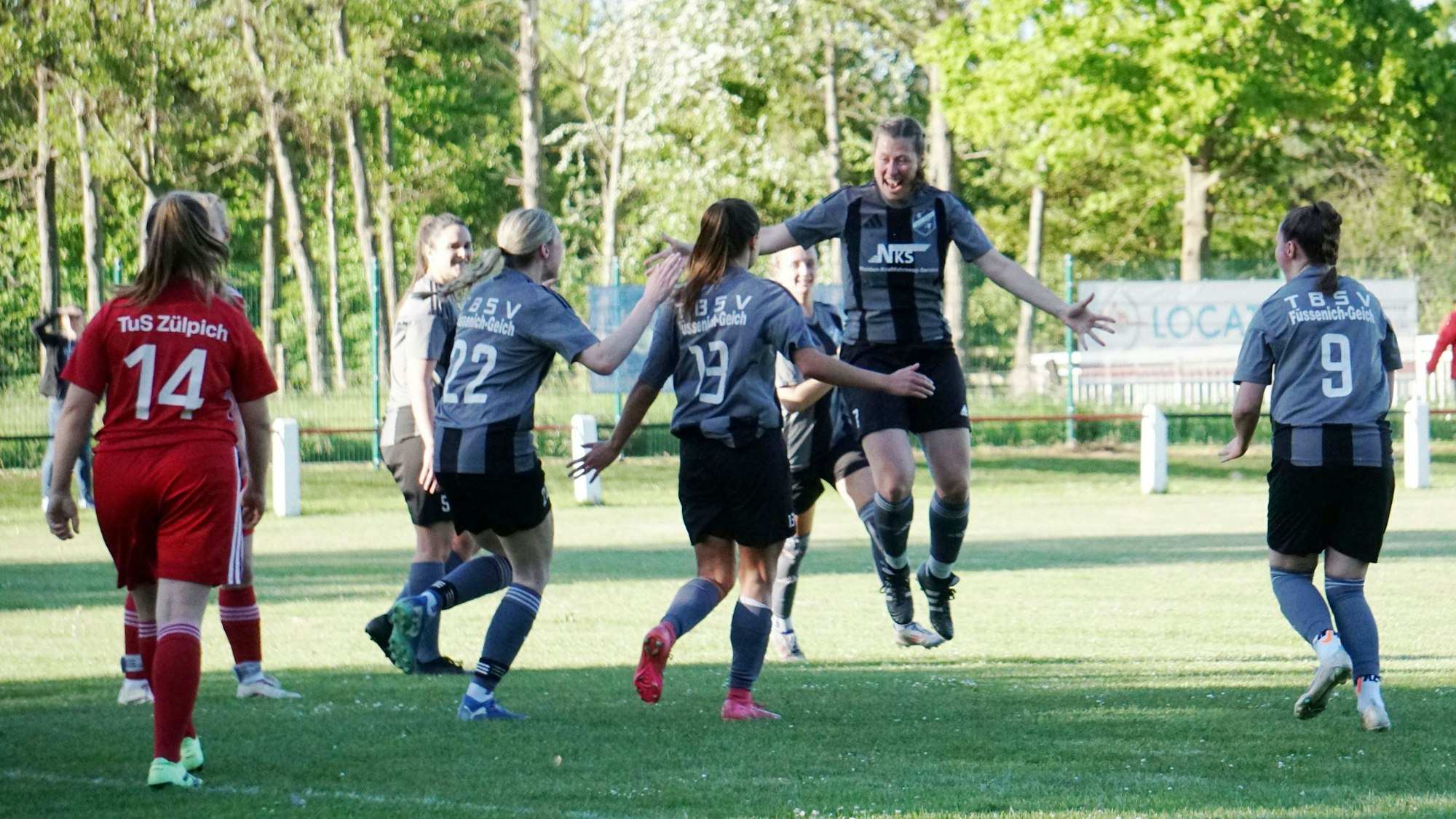 Eine Fußballerin springt nach einem erzielten Tor in die Luft. Mitspielerinnen laufen ihr entgegen.