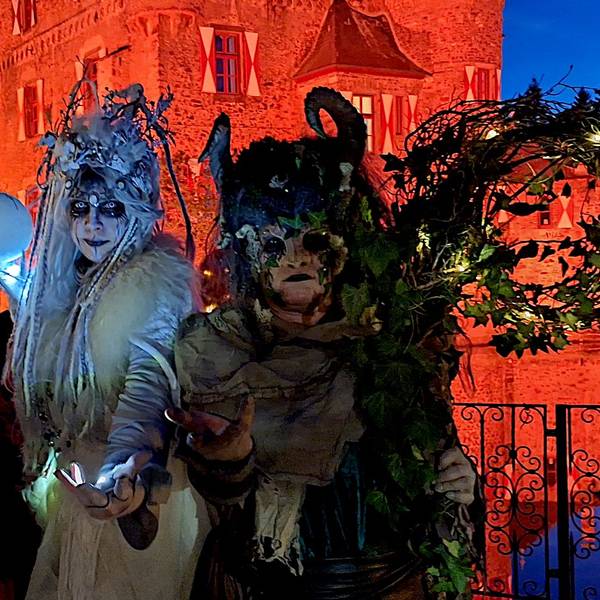 Die drei kostümierten Hexen in aufwendigen Kostümen vor der orange angestrahlten Burg.