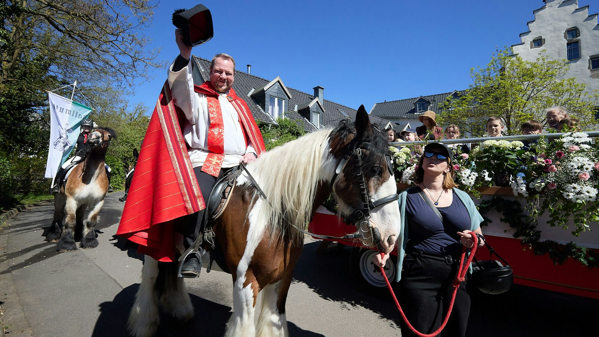 Hoch zu Ross grüßt der Pfarrer mit dem gelupften Birett.