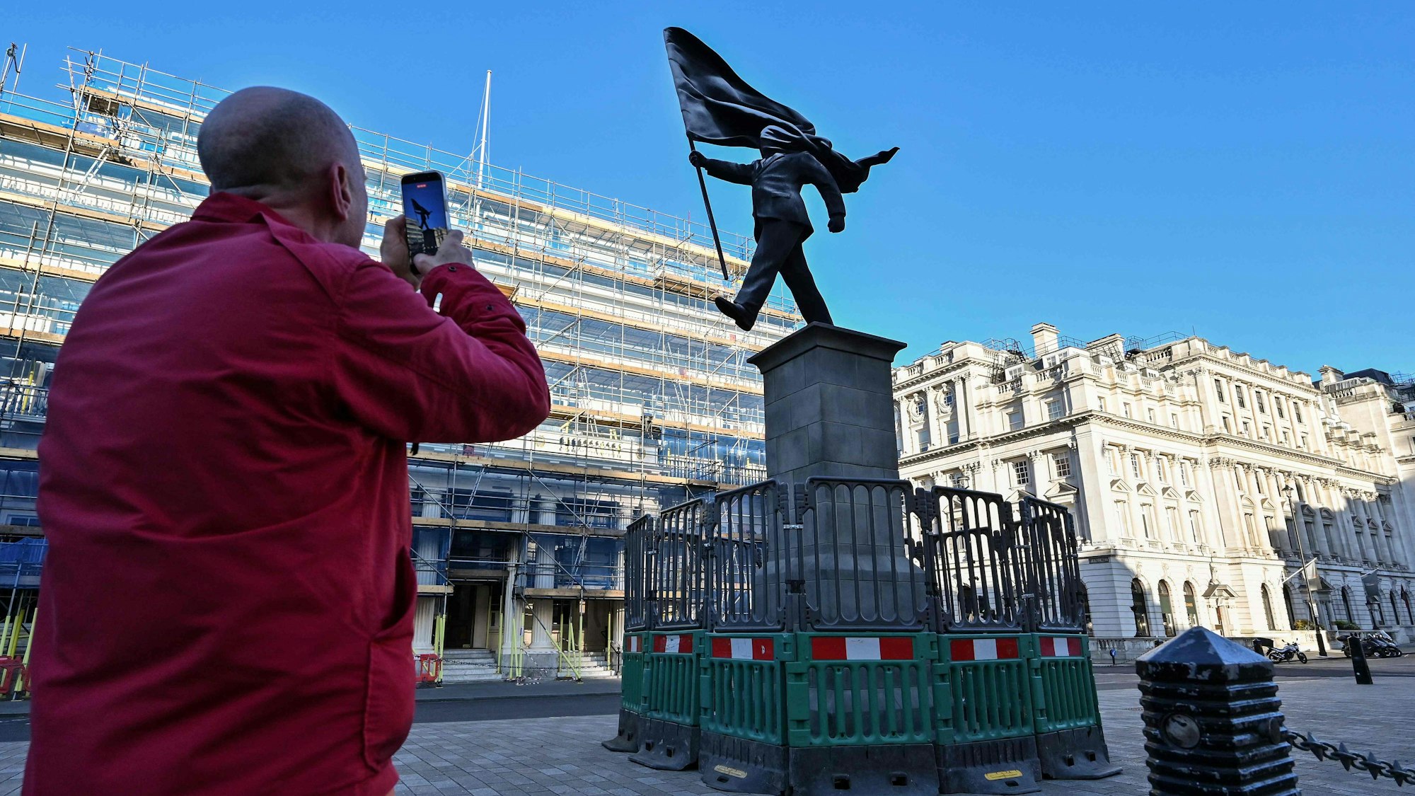 Am Waterloo Place im Zentrum Londons steht eine Statue, die einen Mann zeigt, der eine Flagge hält, die sein Gesicht verdeckt, und die am Sockel mit „Banksy“ unterzeichnet ist.