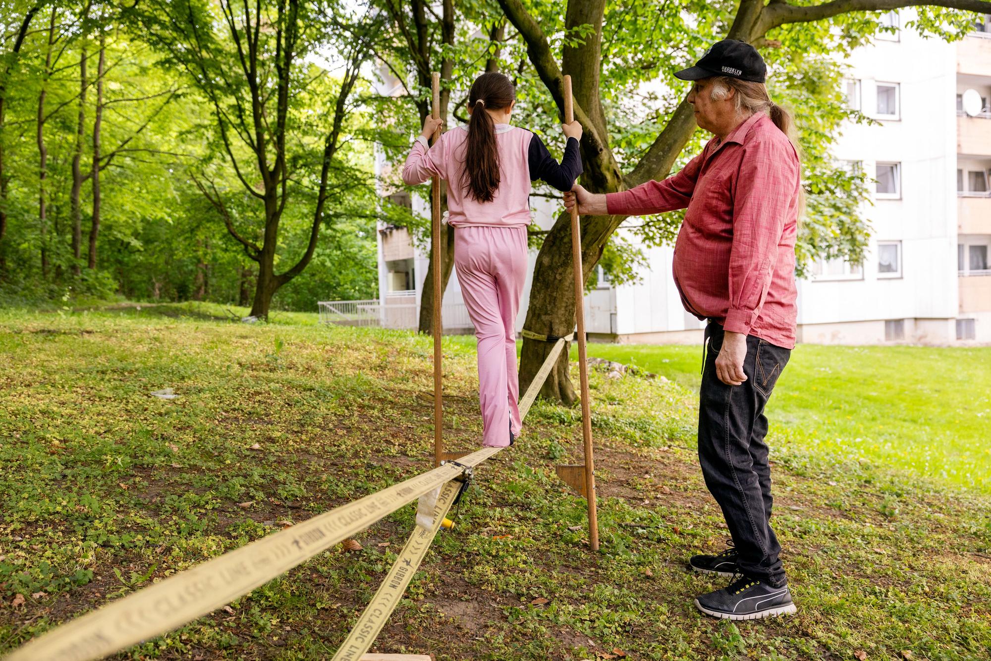 Spierlewerkstatt-Mitarbeiter Georg Höcketstaller begelitet ein Mädchen in der Gernsheimer Straße über die Slackline.