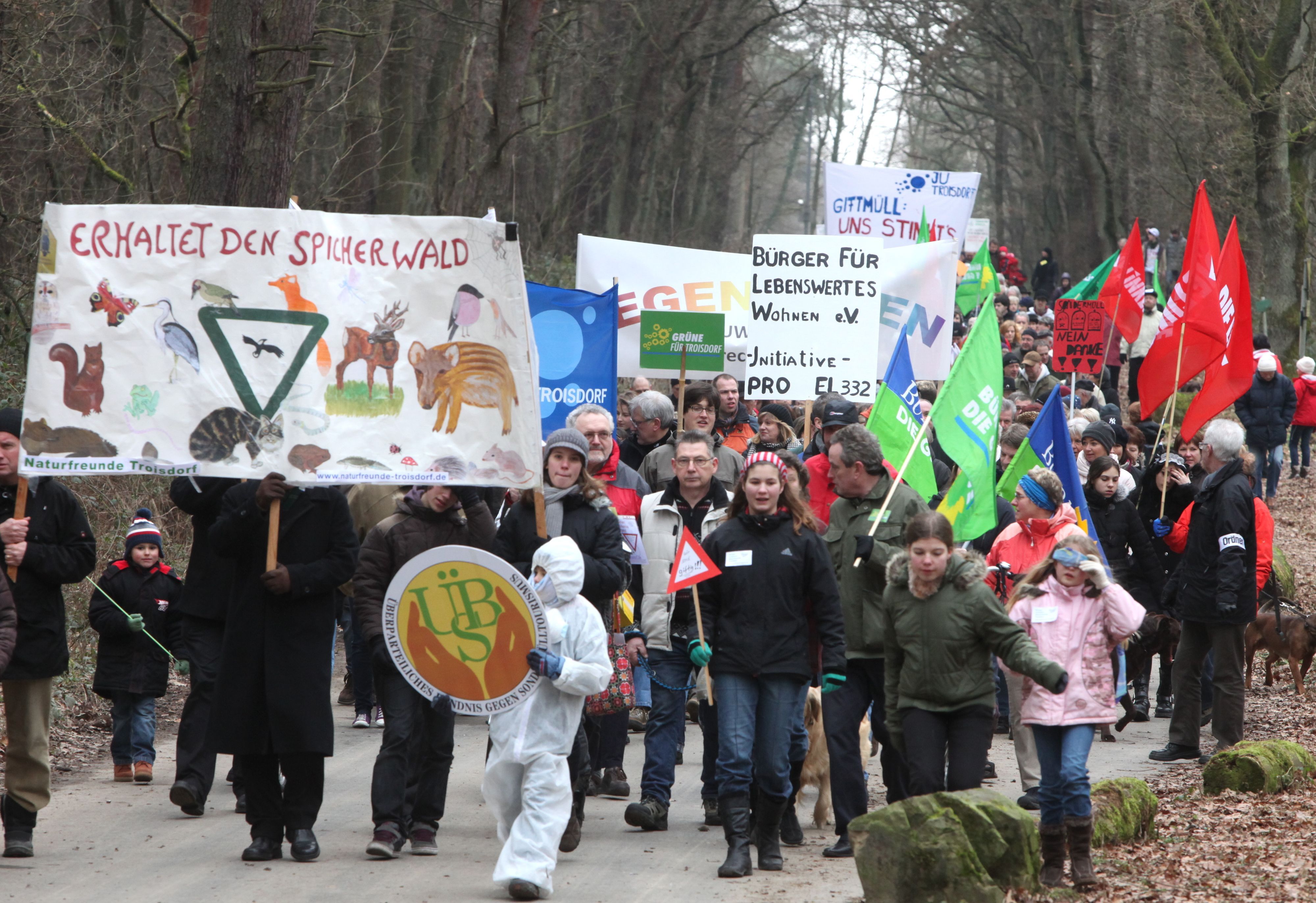 Menschen mit Protesttransparenten auf einer Straße im Wald.