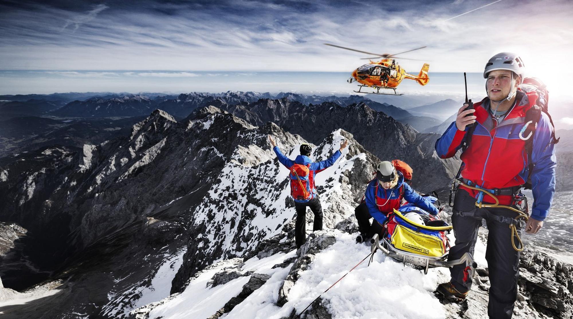 Auch die zweite Staffel der „Bergretter im Einsatz“ zeigt Bergwachteinsätze in den bayerischen Alpen - hautnah und in beeindruckenden Bildern. Drei Angehörige der Bergwacht, die sich mit einer geretteten Person auf einem Berggipfel befinden, weisen einen anfliegenden Hubschrauber ein. (Bild: BR / Timeline Production)