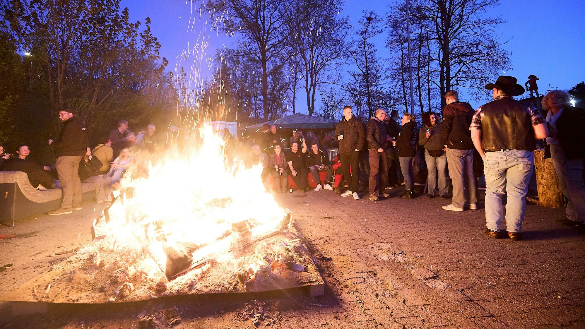 Um das hell lodernde Feuerwehr haben sich viele junge Leute geschart.