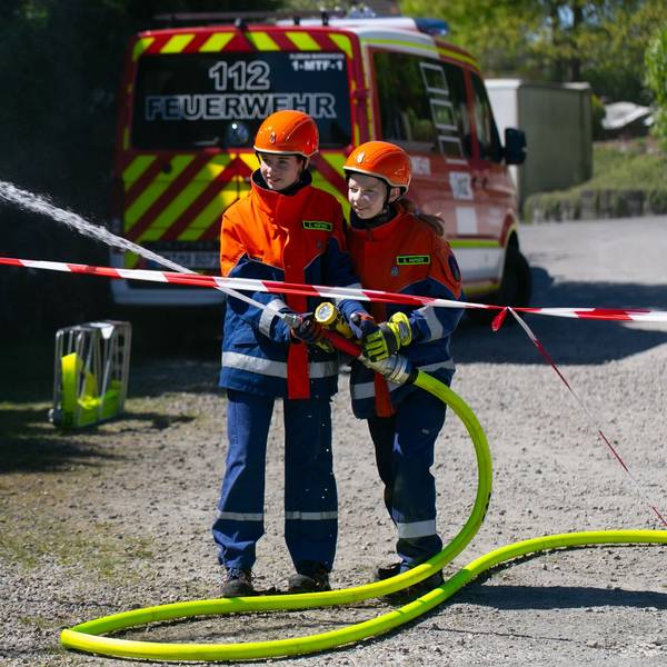 Eine Schauübung zweier Kinder der Kinderfeuerwehr, die mit einem Schlauch löschen.