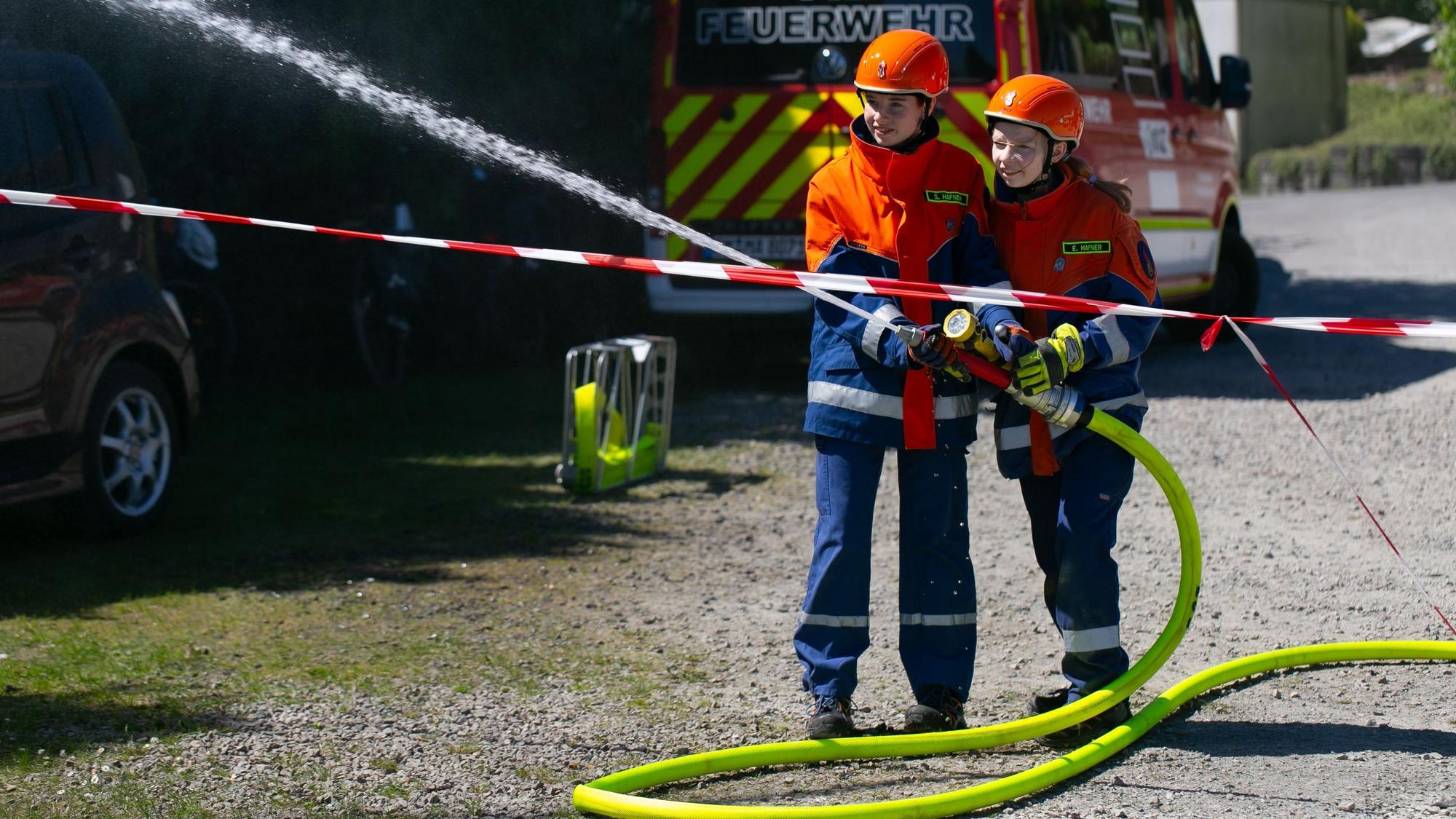 Eine Schauübung zweier Kinder der Kinderfeuerwehr, die mit einem Schlauch löschen.