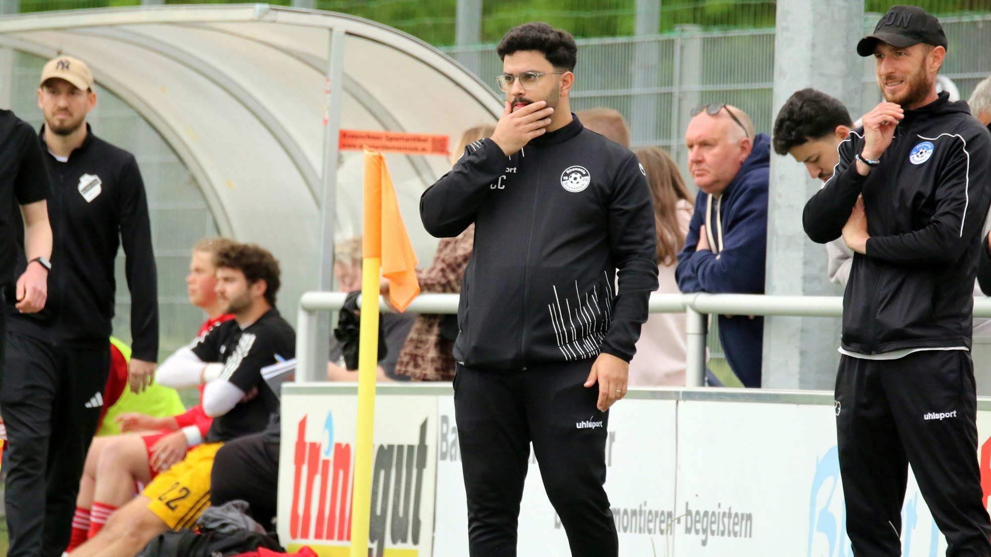 Bessenichs Trainer Can Celik greift sich mit der Hand ins Gesicht. Neben ihm steht Ex-Profi Moritz Hartmann.
