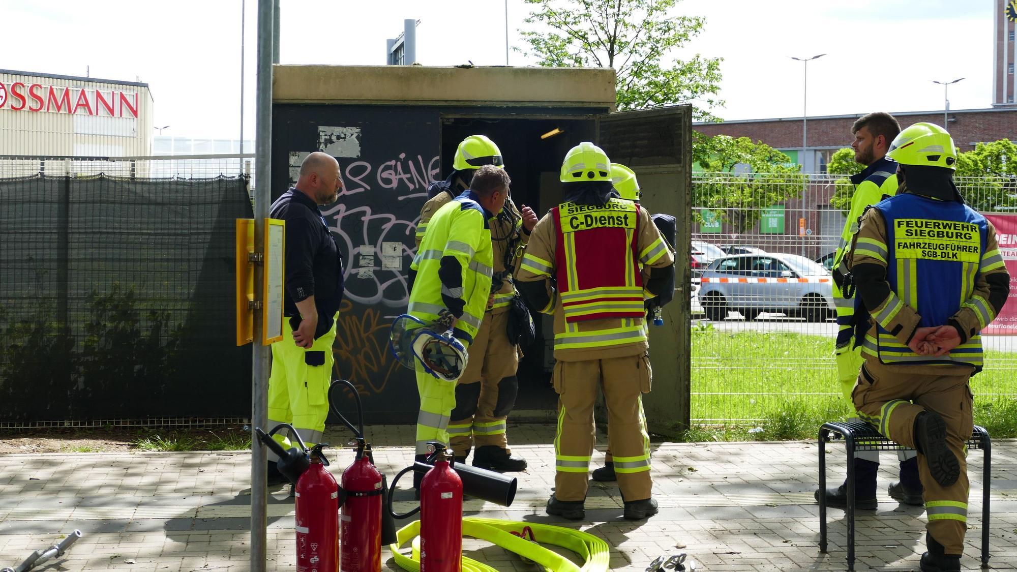 Hier lag offenbar die Ursache: Feuerwehrleute und Westnetz-Mitarbeiter stehen vor der Mittelspannungsschaltstelle an der Wilhelm-Oswald-Straße.