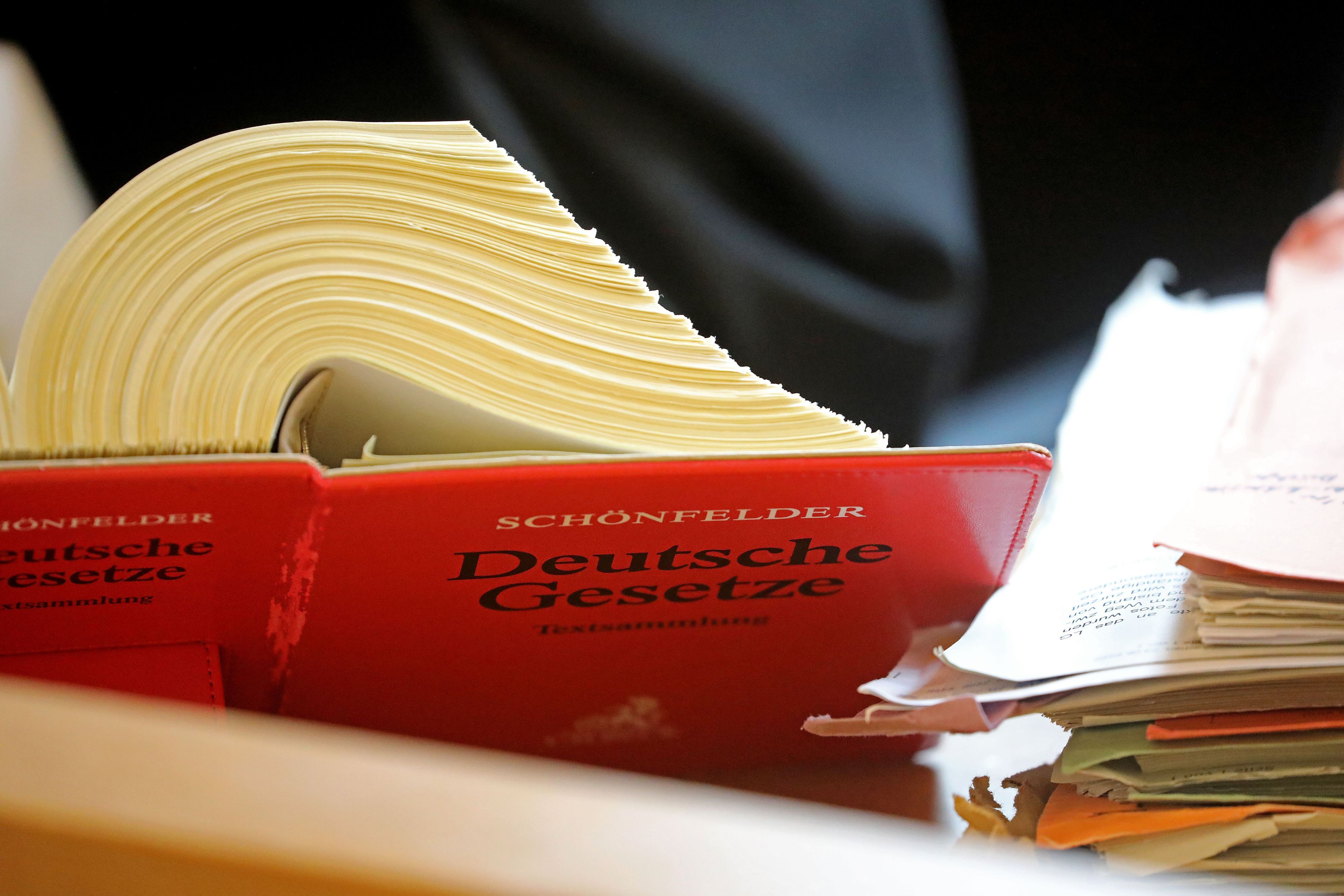 Ein Anwalt sitzt in einem Landgericht vor einem Textband "Deutsche Gesetze".