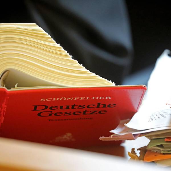 Ein Anwalt sitzt in einem Landgericht vor einem Textband "Deutsche Gesetze".