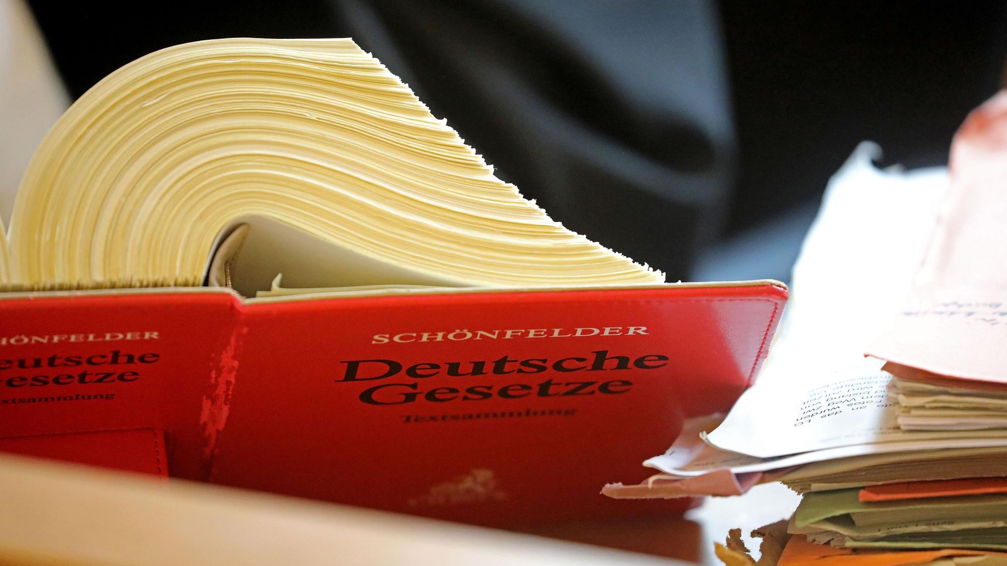 Ein Anwalt sitzt in einem Landgericht vor einem Textband "Deutsche Gesetze".