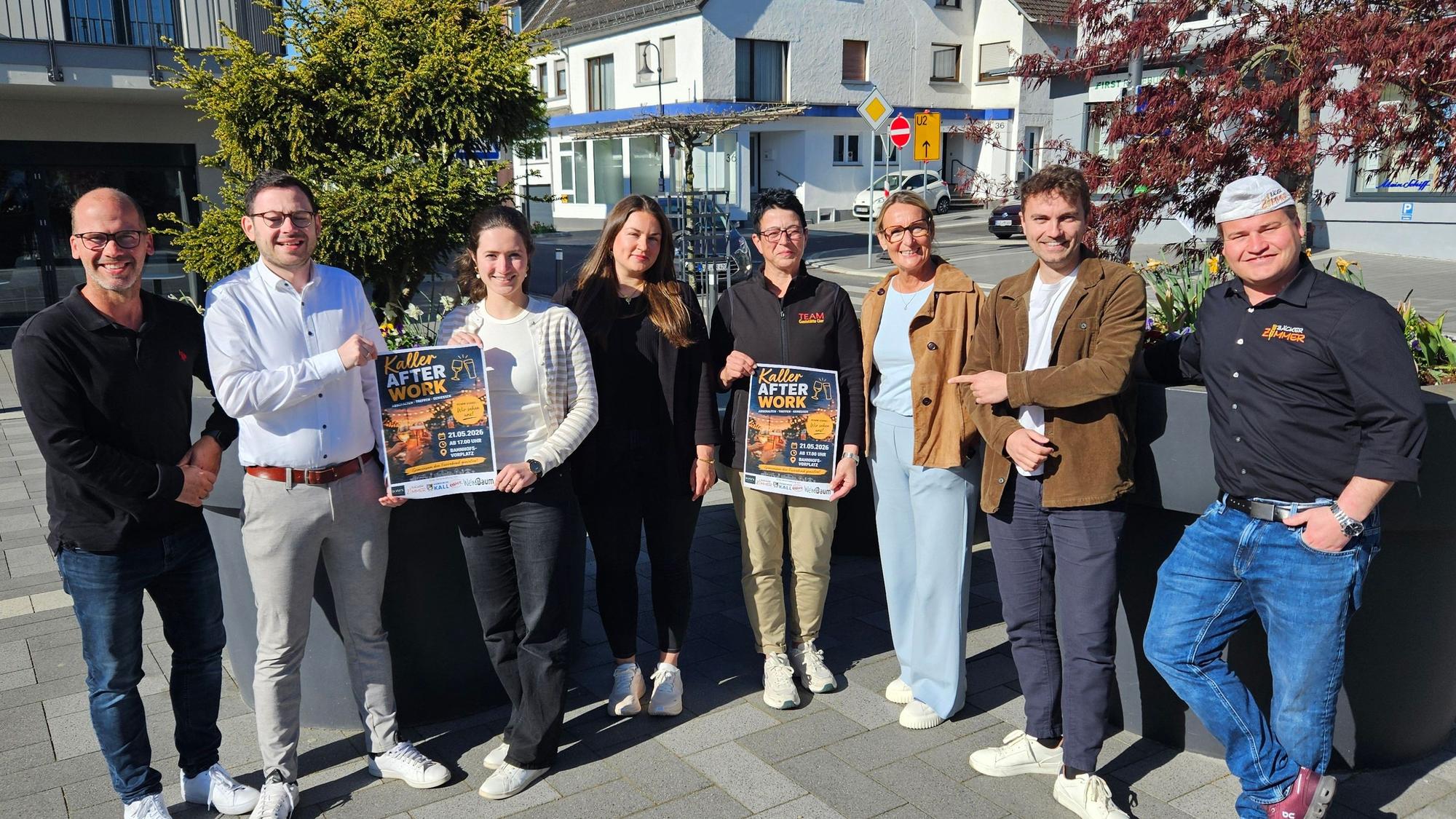 Vier Männer und vier Frauen stehen auf dem Bahnhofsvorplatz nebeneinander und präsentieren zwei Plakate.