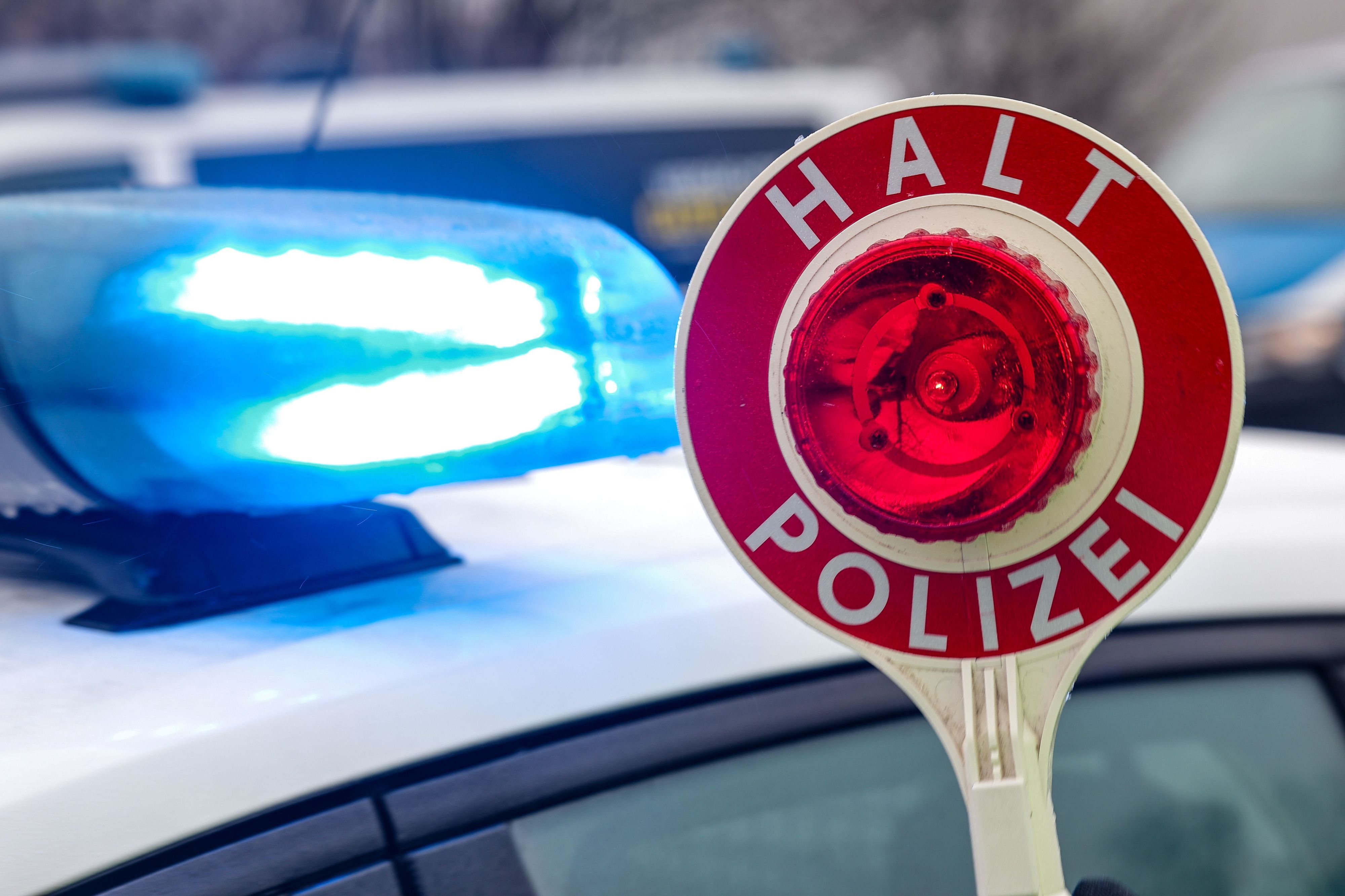 Ein Polizist hält eine Polizeikelle für eine Kontrolle auf einem Parkplatz an der Autobahn.