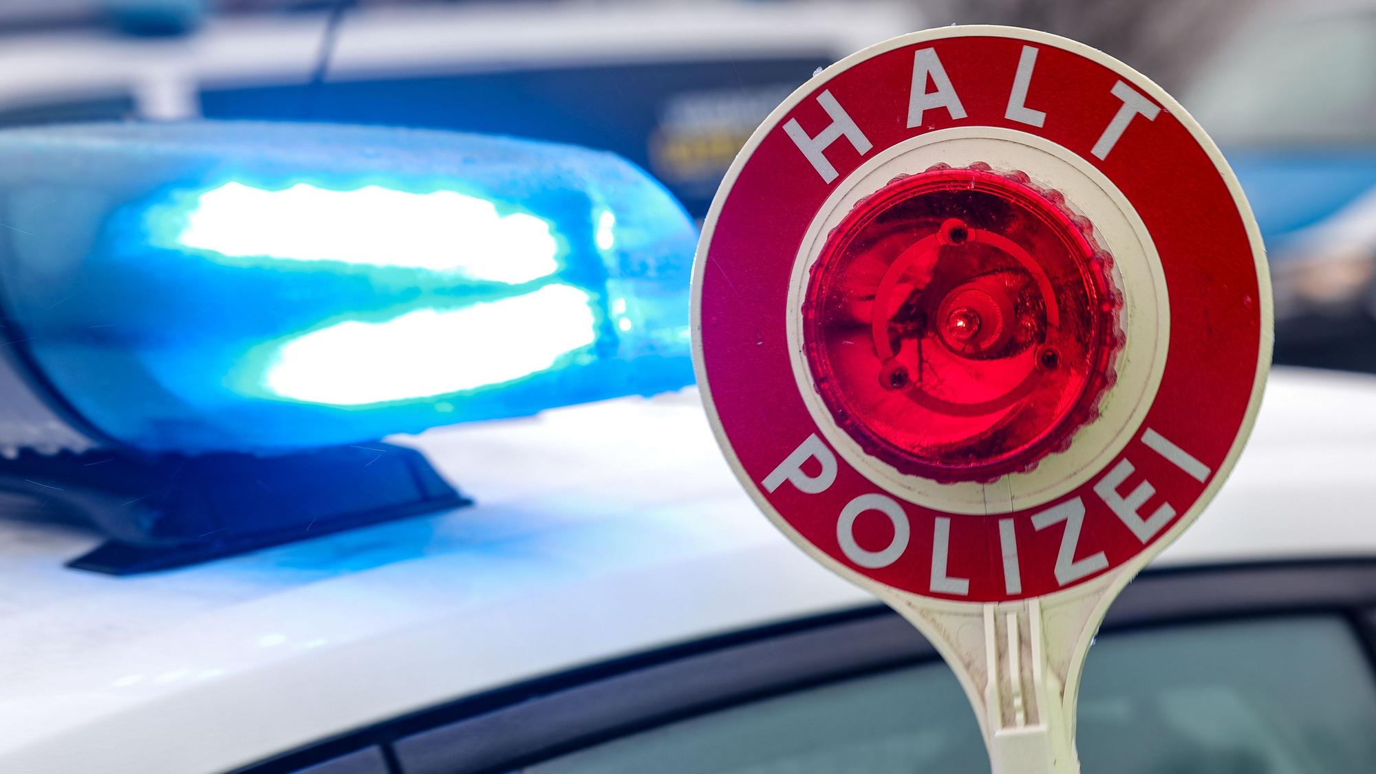 Ein Polizist hält eine Polizeikelle für eine Kontrolle auf einem Parkplatz an der Autobahn.