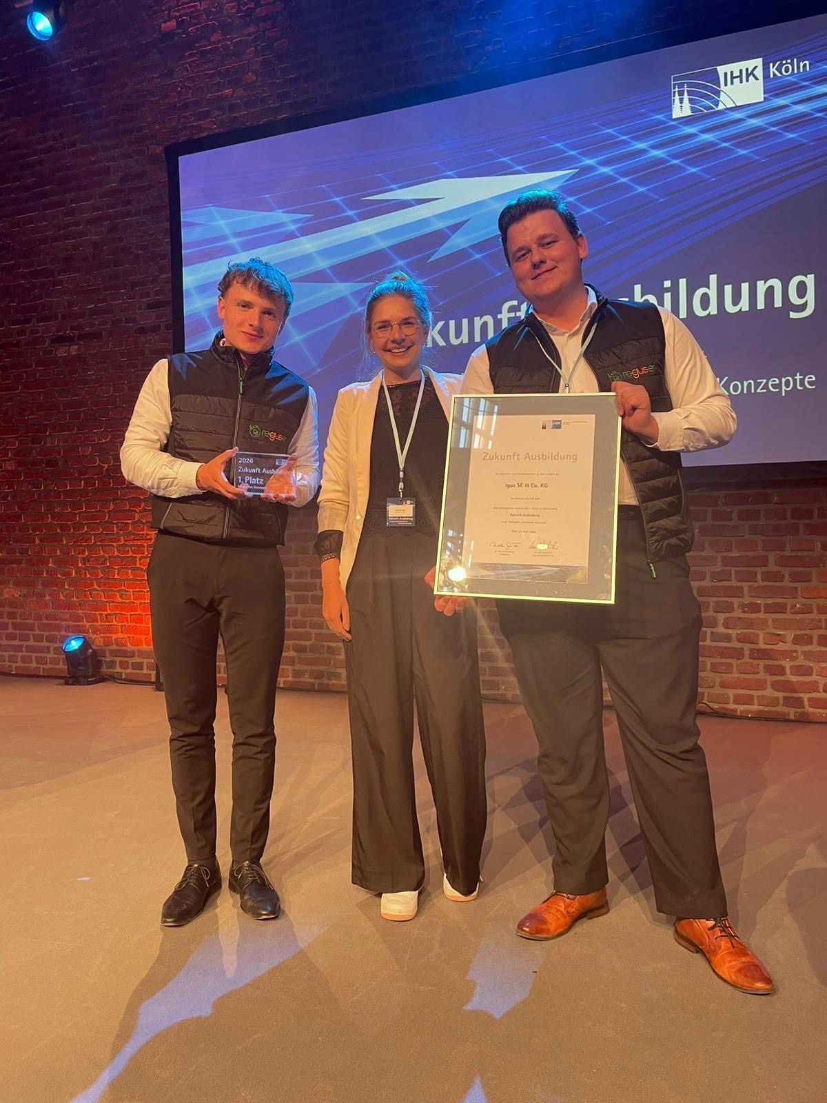 Leander Plum (l.) und Noah Smieskol (r.), beide duale Studenten bei Igus, nahmen gemeinsam mit ihrer Ausbildungsleiterin Michelle Haas (M.) den IHK-Preis „Zukunft Ausbildung“ für das Reguse-Projekt entgegen.