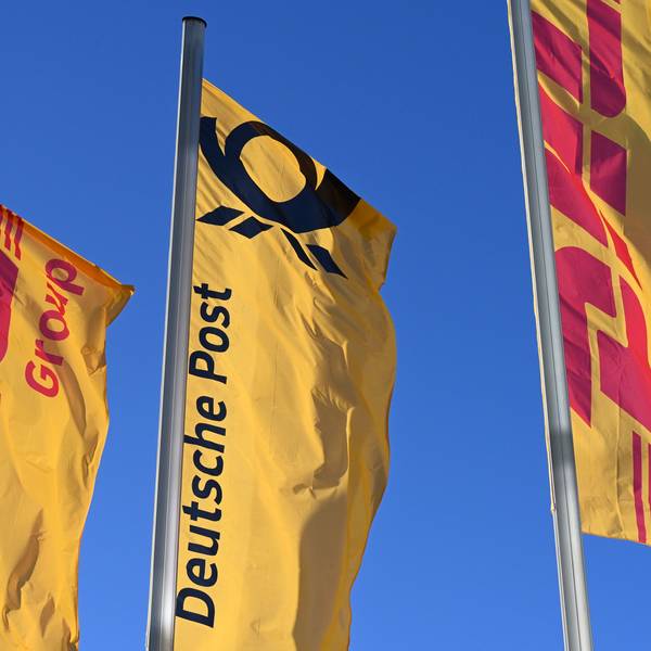 Fahnen des Logistikkonzerns DHL und seiner Brieftochter Deutsche Post wehen vor der Konzernzentrale an Masten. Der Konzern möchte sich von Deutsche Post AG zu DHL AG umbenennen.