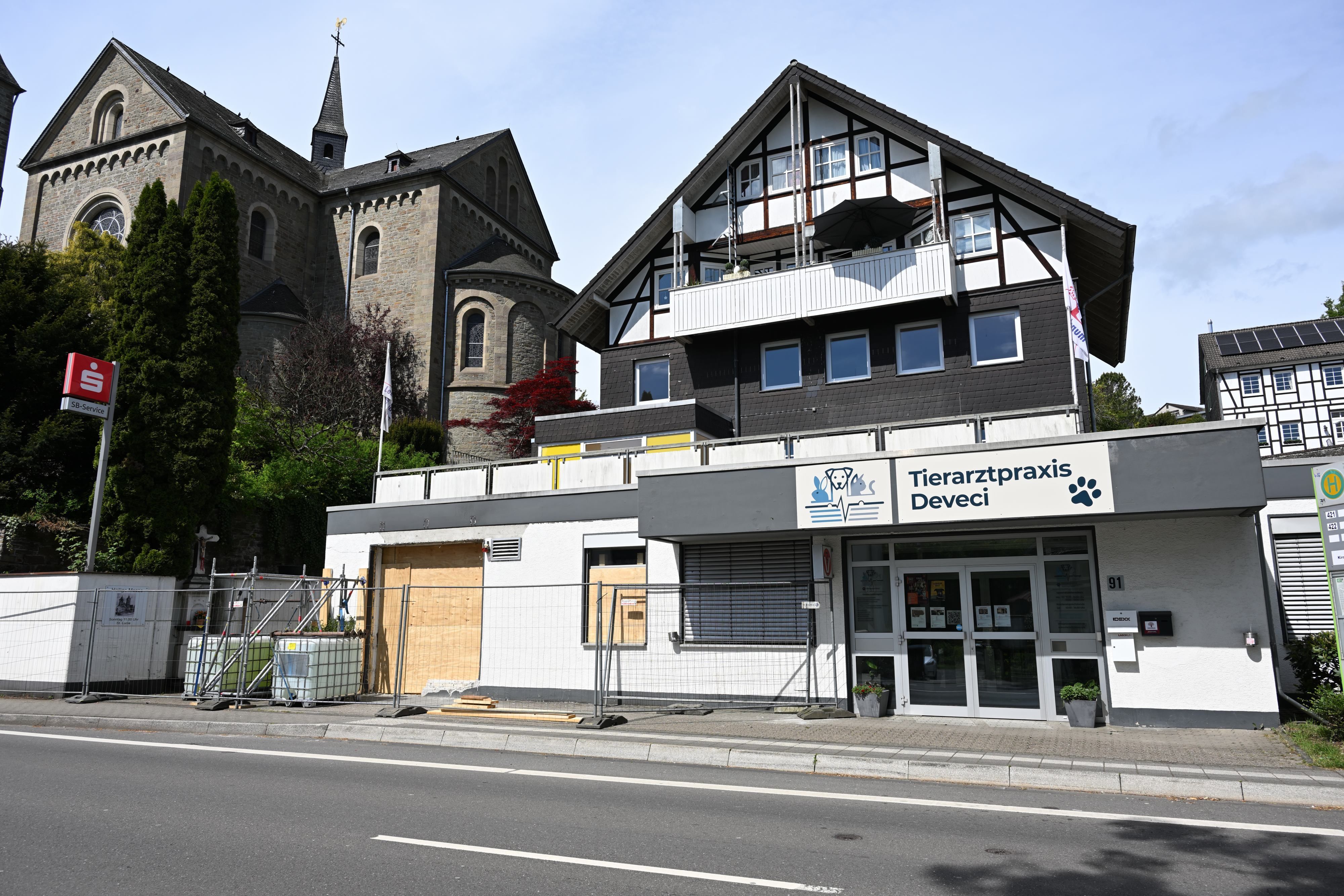 Zu sehen ist ein Gebäude mit Brettern anstelle von Fenstern und einem Bauzaun drumherum.