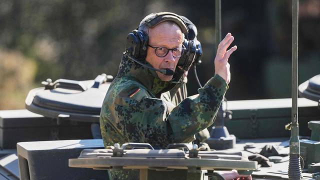Bundeskanzler Friedrich Merz winkt aus einem Panzer.