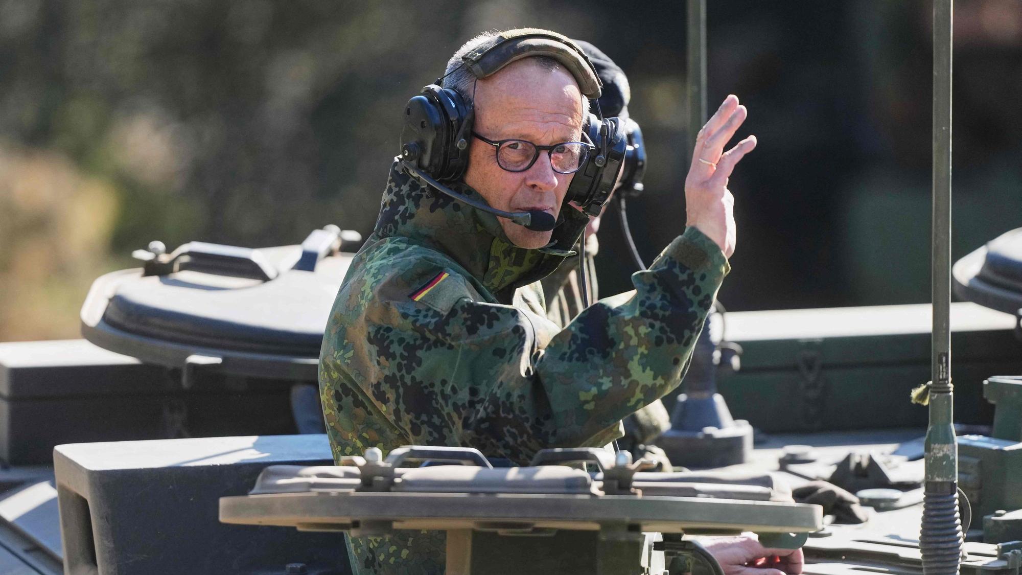 Bundeskanzler Friedrich Merz winkt aus einem Panzer.