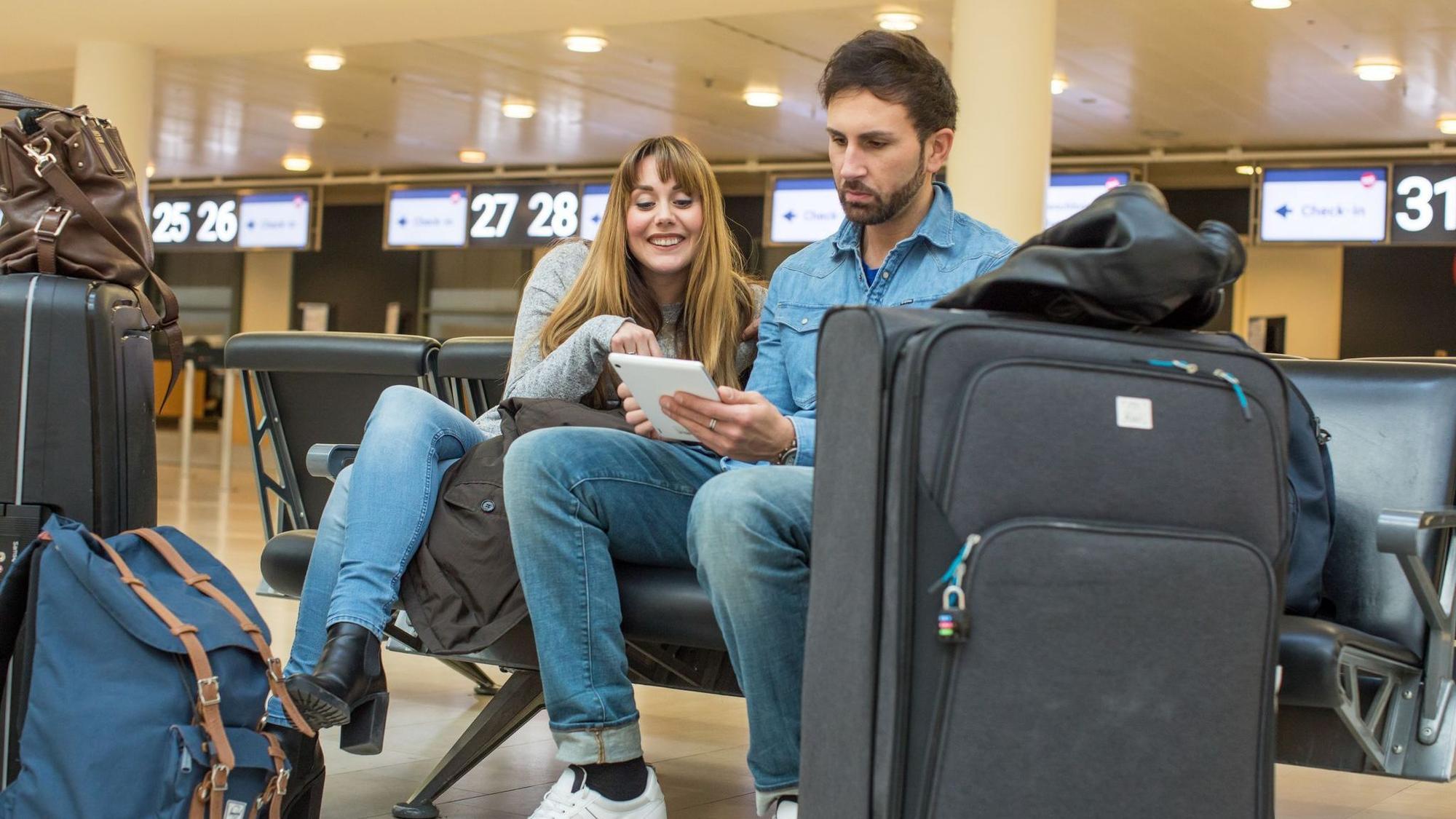 Ein Paar sitzt am Flughafen in der Check-In-Halle