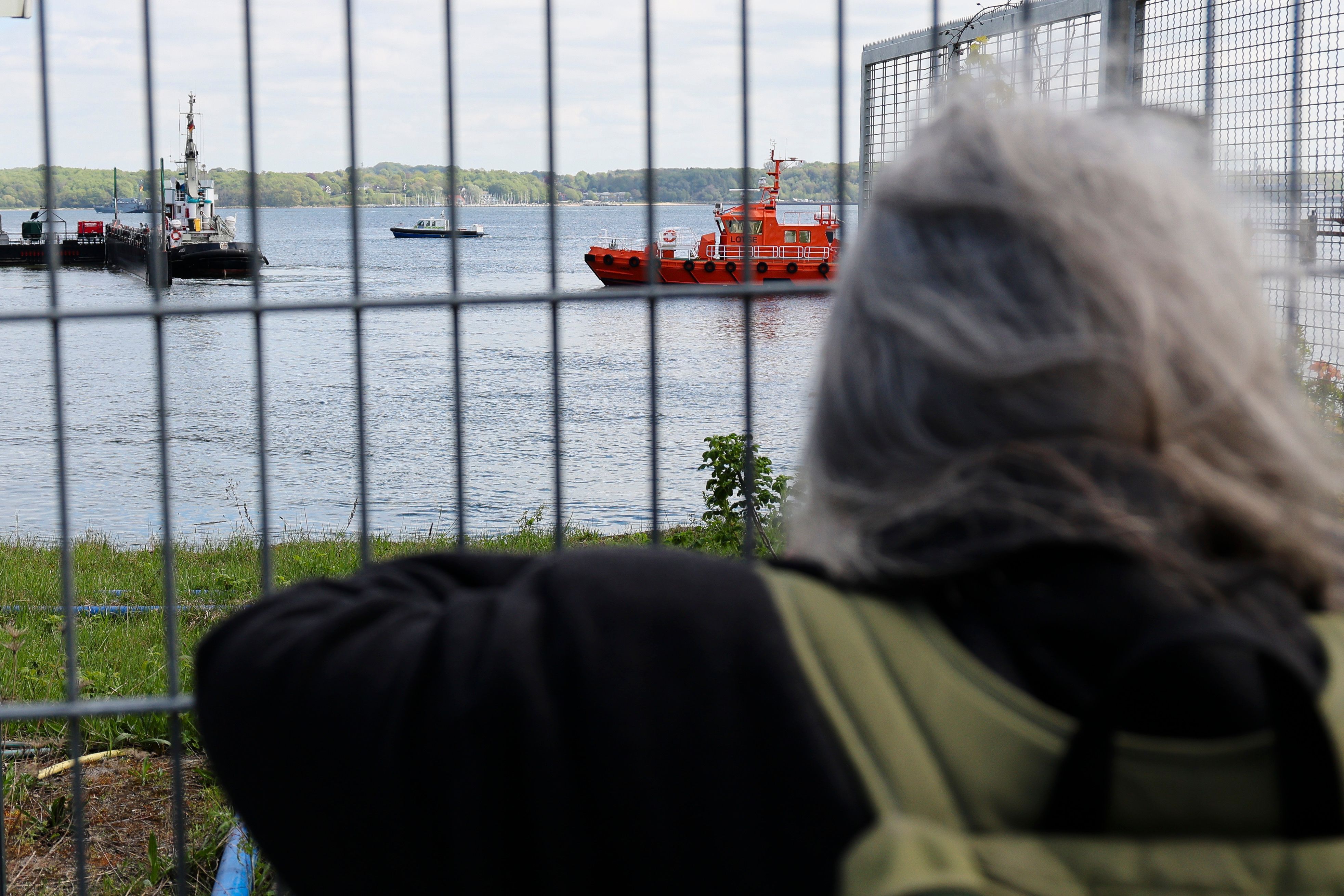 Eine Frau fotografiert am Montag den Schlepper „Robin Hood“ im Kieler Scheerhafen. Das Schiff begleitete den Transport des gestrandeten Buckelwals auf dem Weg zurück in die Nordsee.