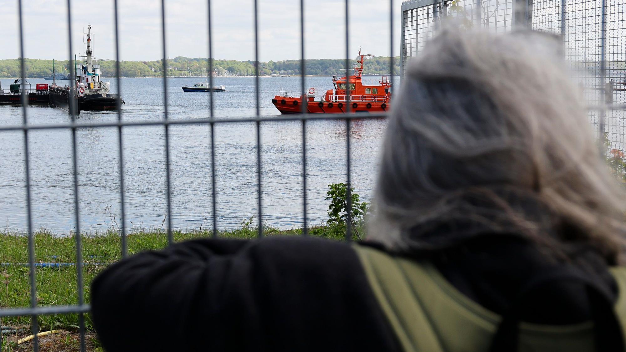 Eine Frau fotografiert am Montag den Schlepper „Robin Hood“ im Kieler Scheerhafen. Das Schiff begleitete den Transport des gestrandeten Buckelwals auf dem Weg zurück in die Nordsee.