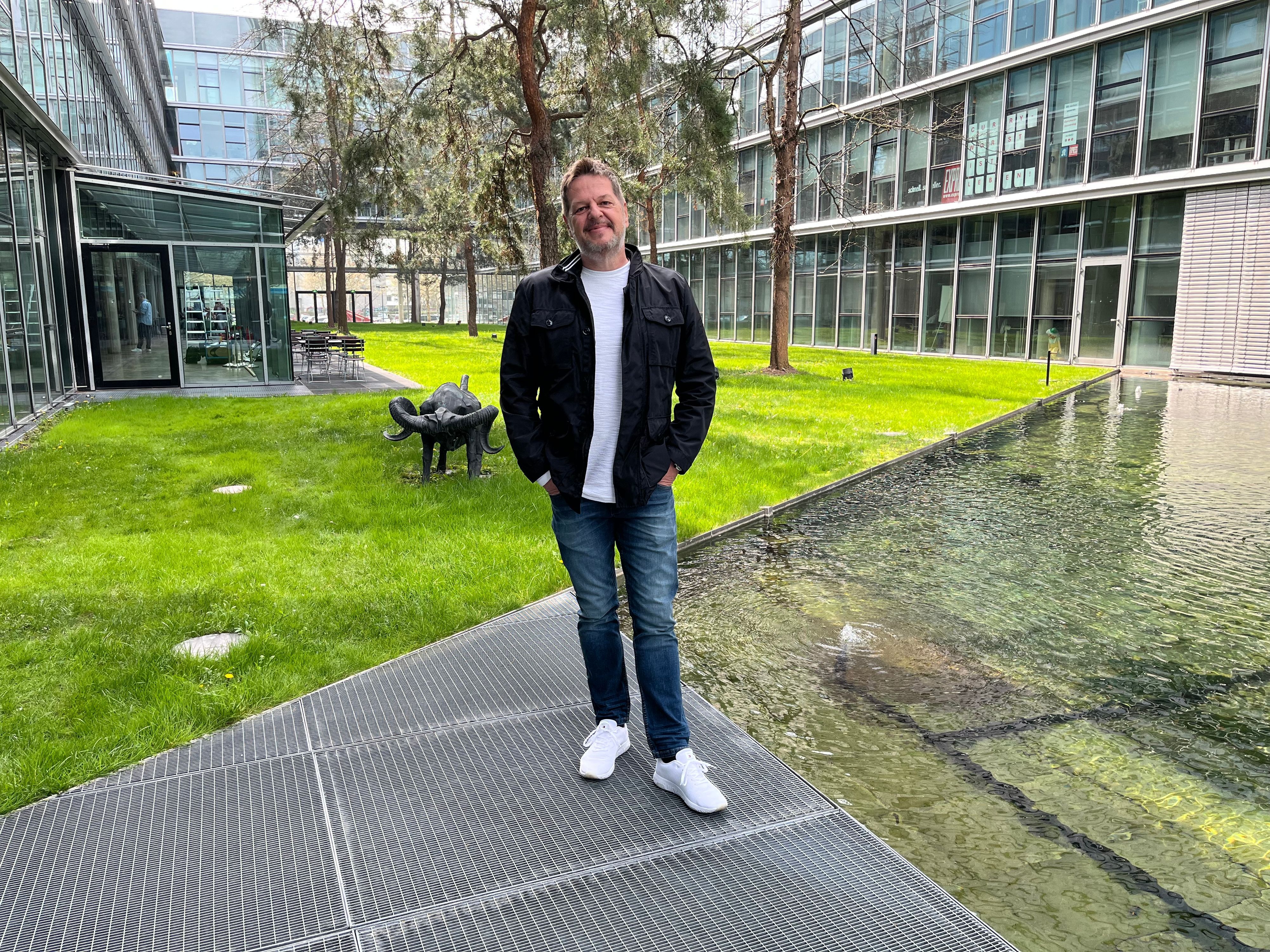 Linus Geschke steht in einem grünen Innenhof