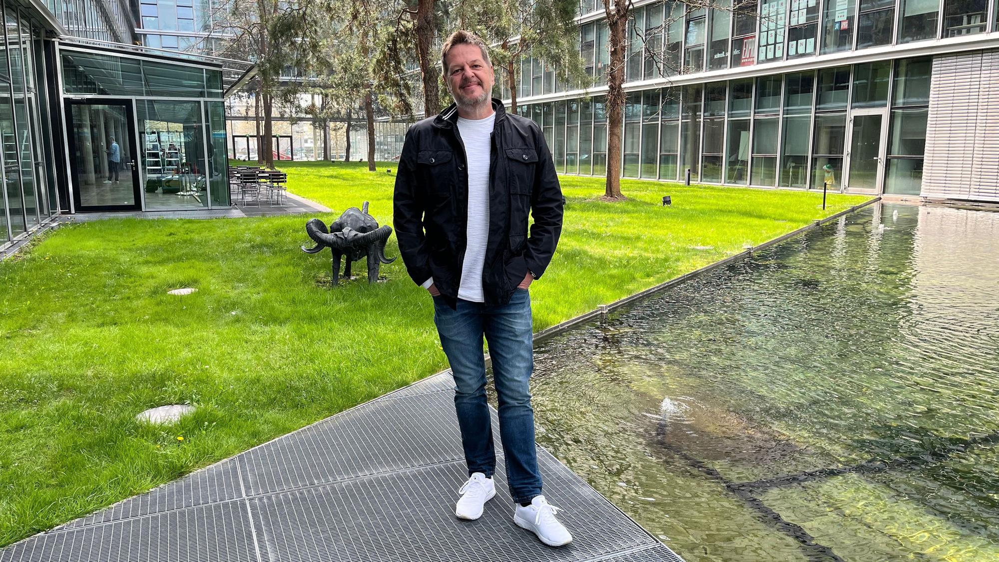 Linus Geschke steht in einem grünen Innenhof