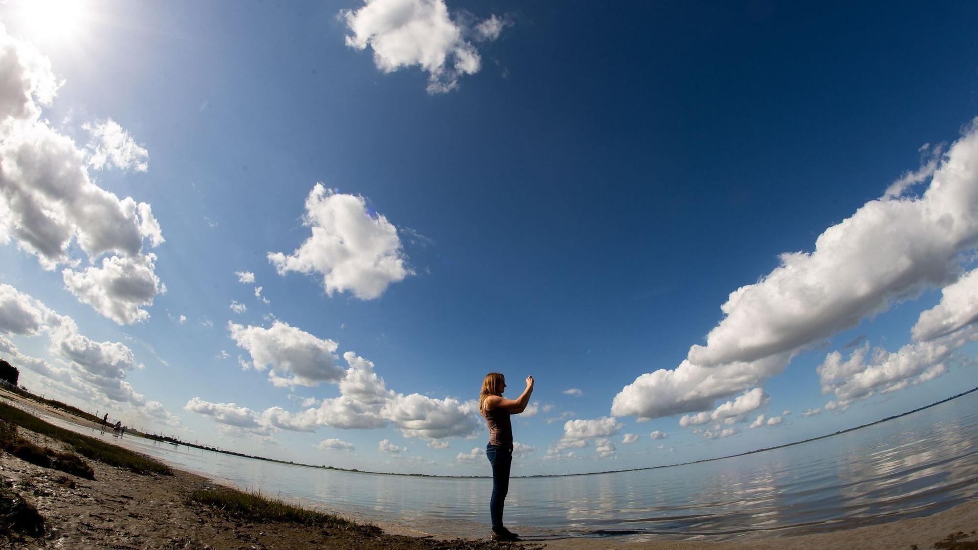 Frau fotografiert mit einem Smartphone die Landschaft