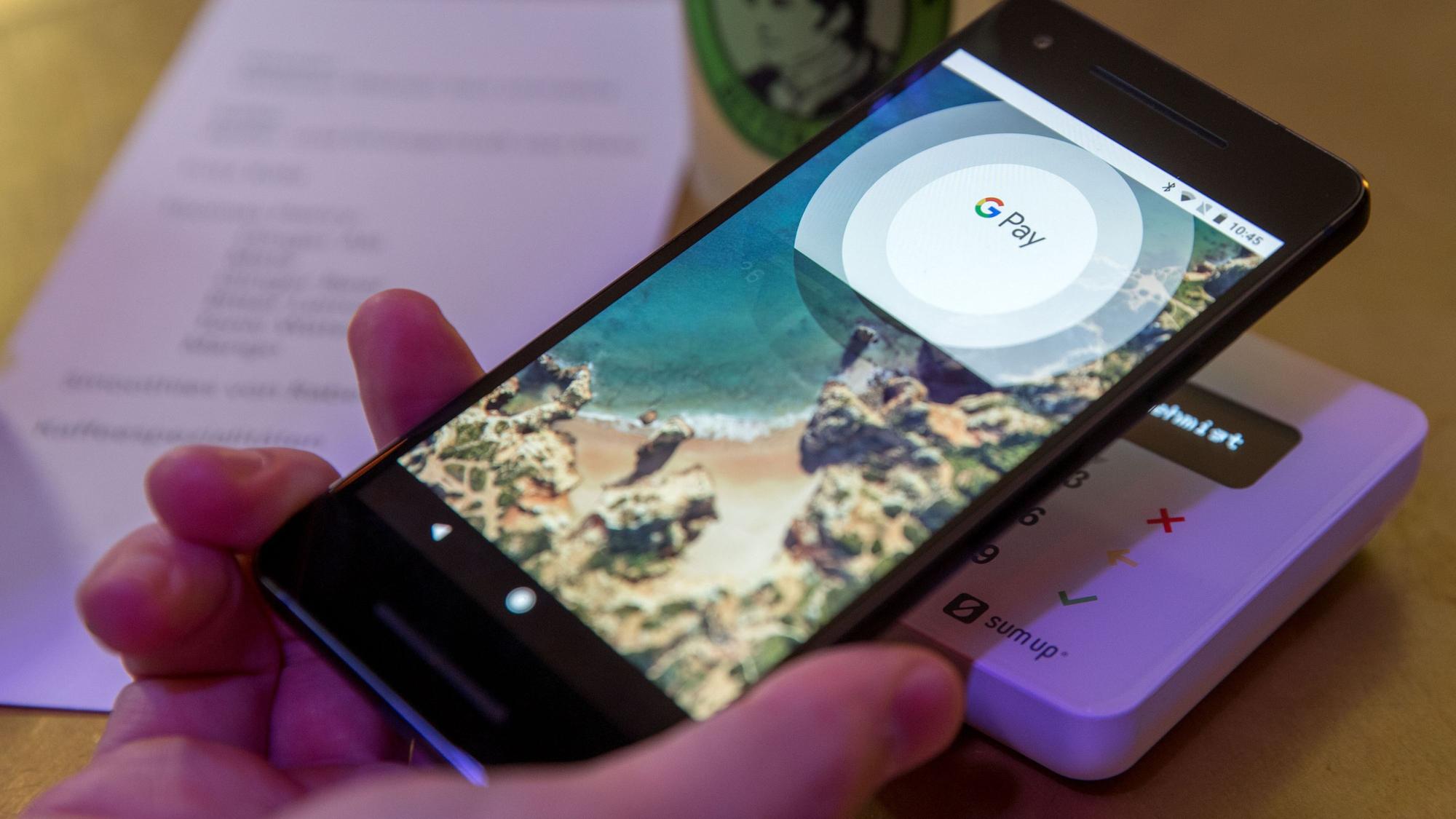 Ein Gast demonstriert mit einem Smartphone und der App des neuen Bezahldienstes Google Pay in einem Cafe das Bezahlen mit dem Handy.