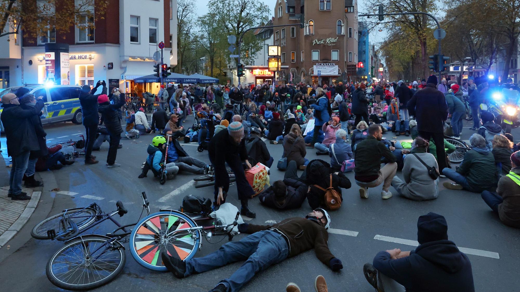 Demonstranten stehen und liegen auf einer Straßenkreuzung.