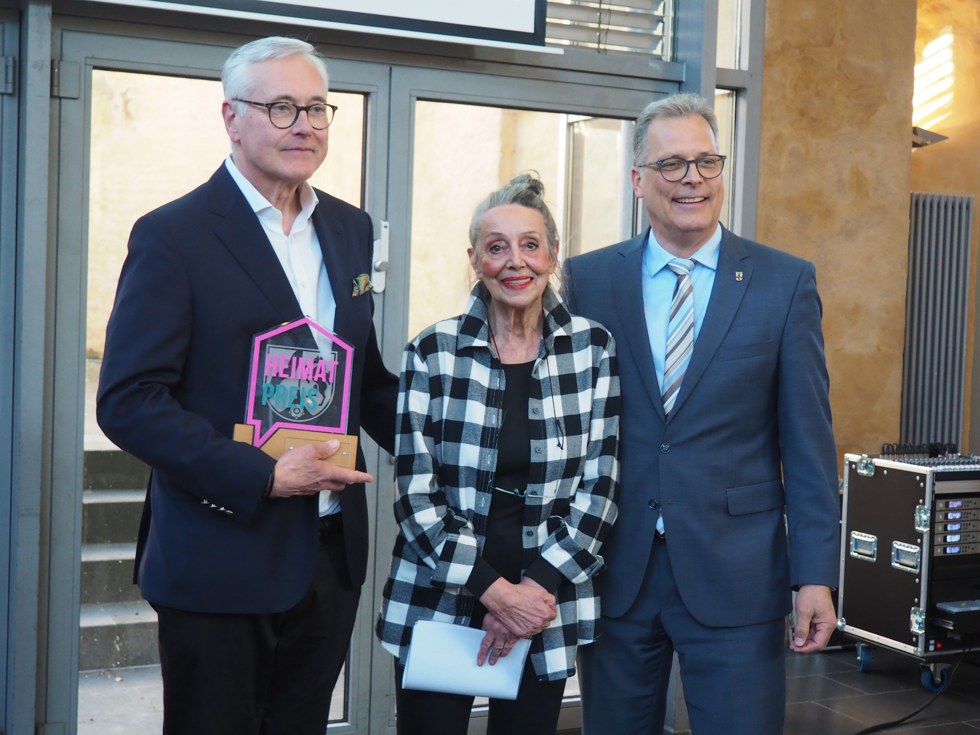 Ralf Engels, Margrit Adams-Scheuer und Bürgermeister Ulf Hürtgen stehen nebeneinander, Engels hält die gläserne Trophäe.