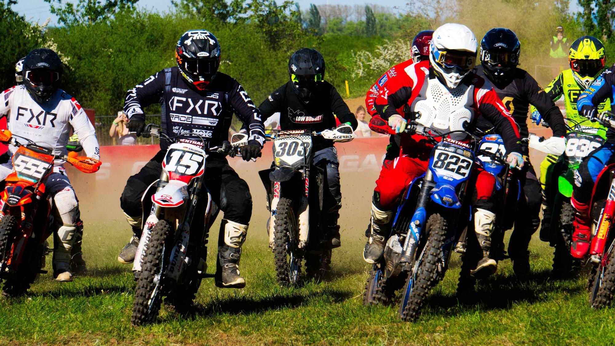 Zahlreiche Motocross-Maschinen fahren beinahe nebeneinander über die Strecke.