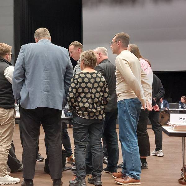Männer und Frauen beraten in einem Sitzungssaal.