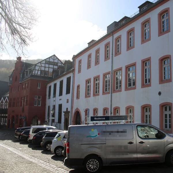 Autos stehen vor dem Grundschulgebäude. Im Hintergrund ist das benachbarte Rathaus zu erkennen.
