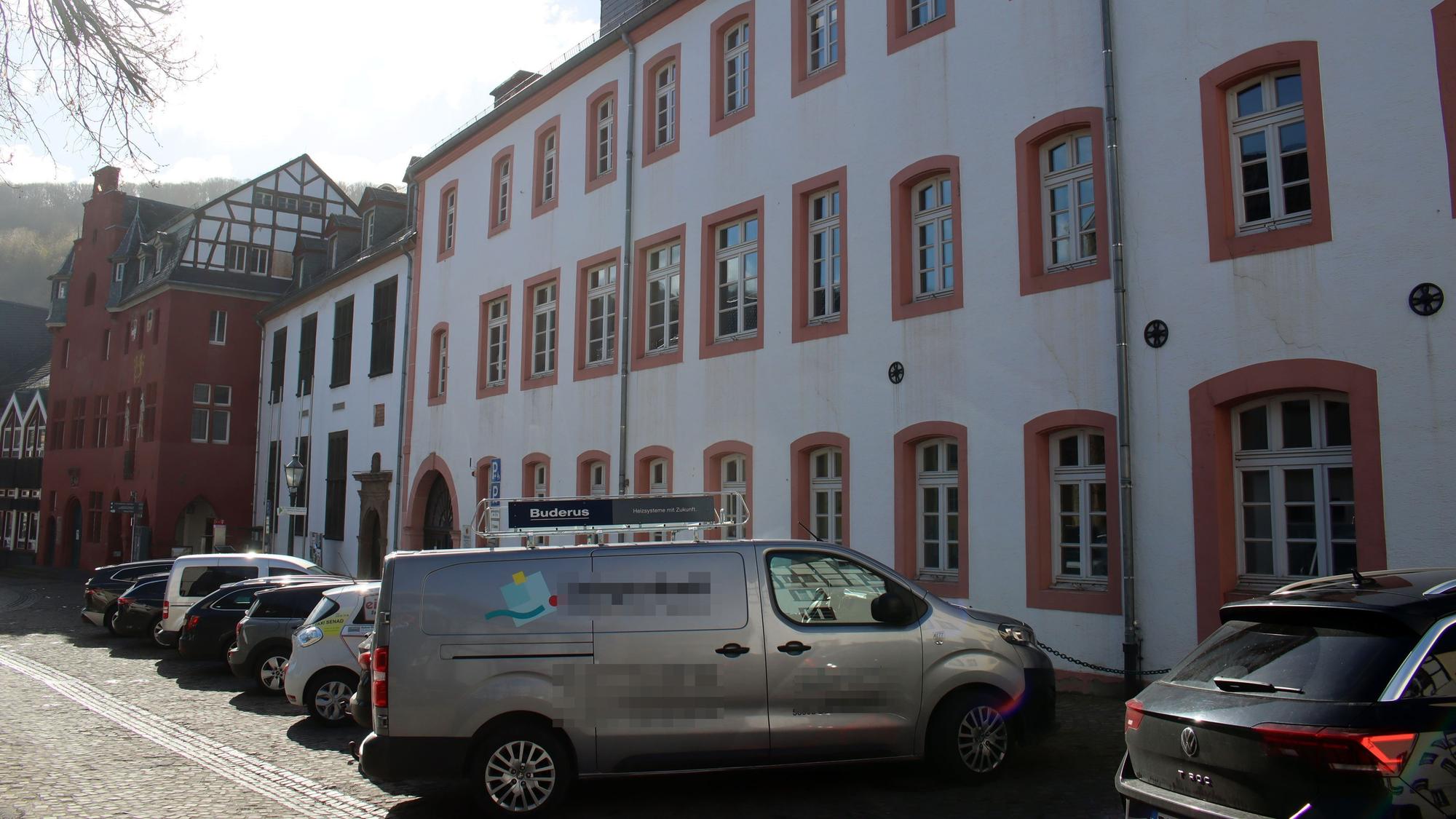 Autos stehen vor dem Grundschulgebäude. Im Hintergrund ist das benachbarte Rathaus zu erkennen.