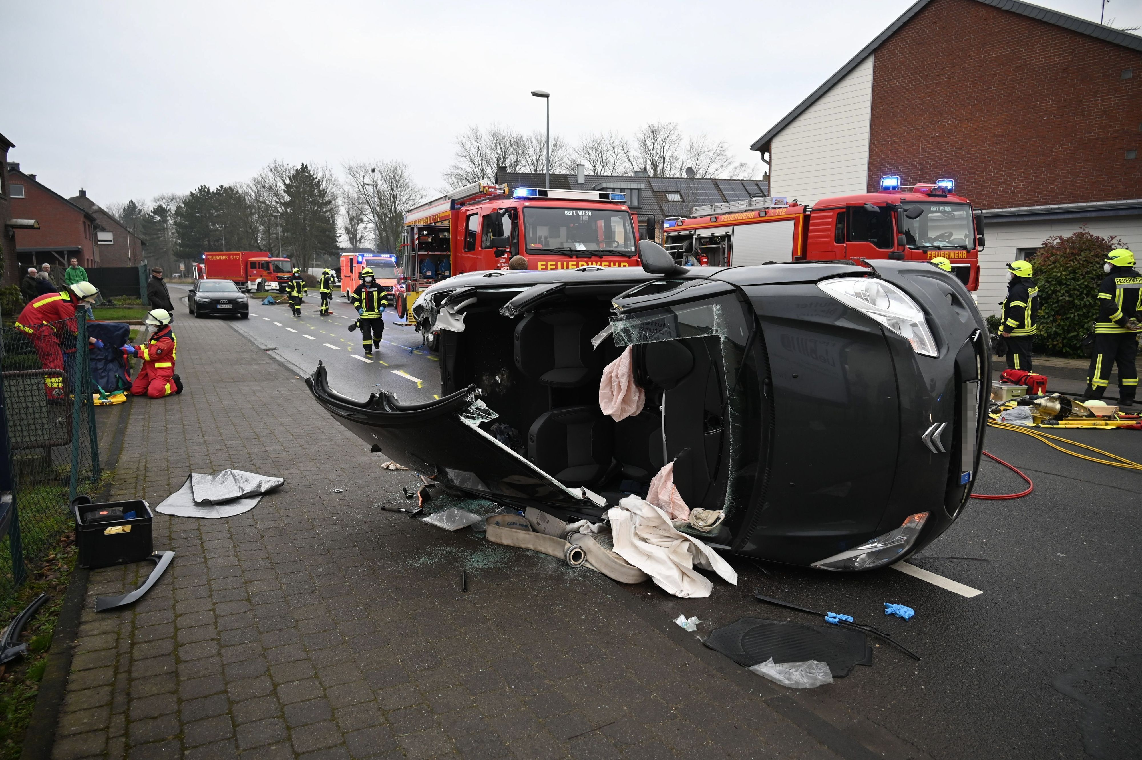 Zu sehen ist ein auf der Seite liegendes Auto, dessen Dach von der Feuerwehr aufgeschnitten wurde.