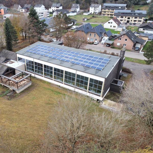 Das Drohnenfoto zeigt ddas Schwimmbad in Kall aus der Vogelperspektive. Auf dem Dach sind PV-Module installiert.