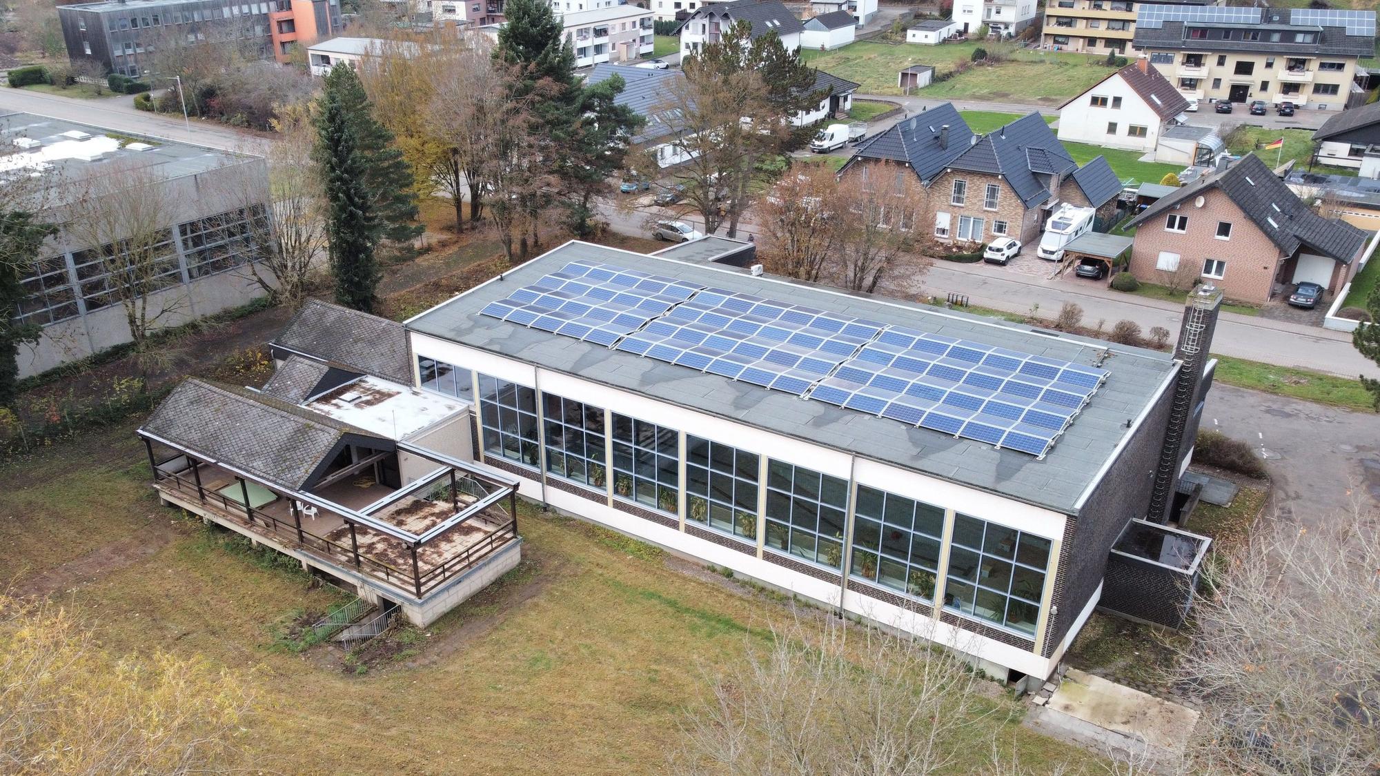 Das Drohnenfoto zeigt ddas Schwimmbad in Kall aus der Vogelperspektive. Auf dem Dach sind PV-Module installiert.
