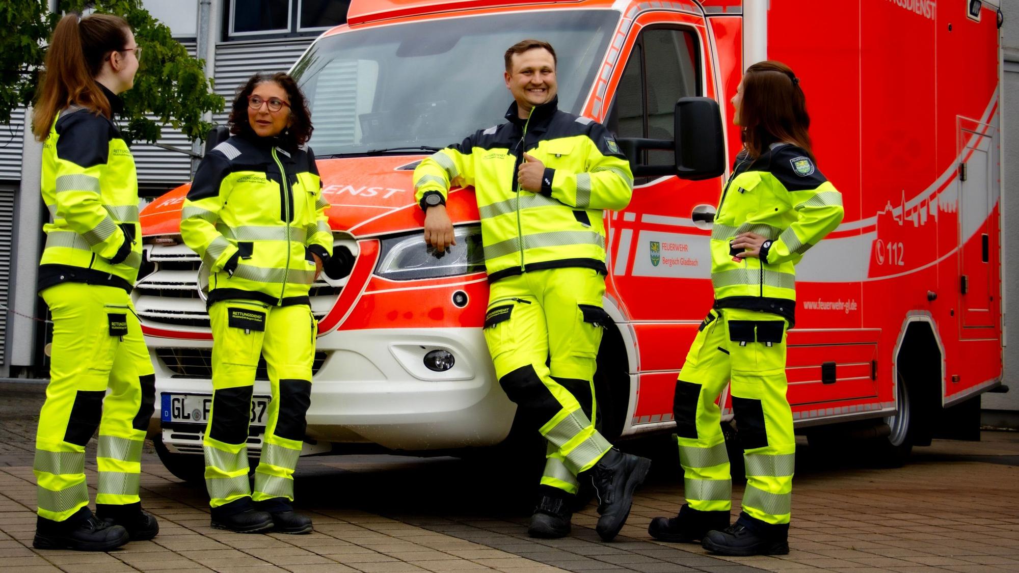 Rettungsdienstmitarbeitende stehen vor einem Rettungswagen der Feuerwehr Bergisch Gladbach.