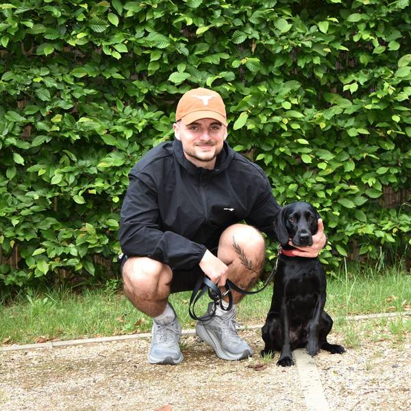 Das Foto zeigt einen Mann mit einem schwarzen Hund.