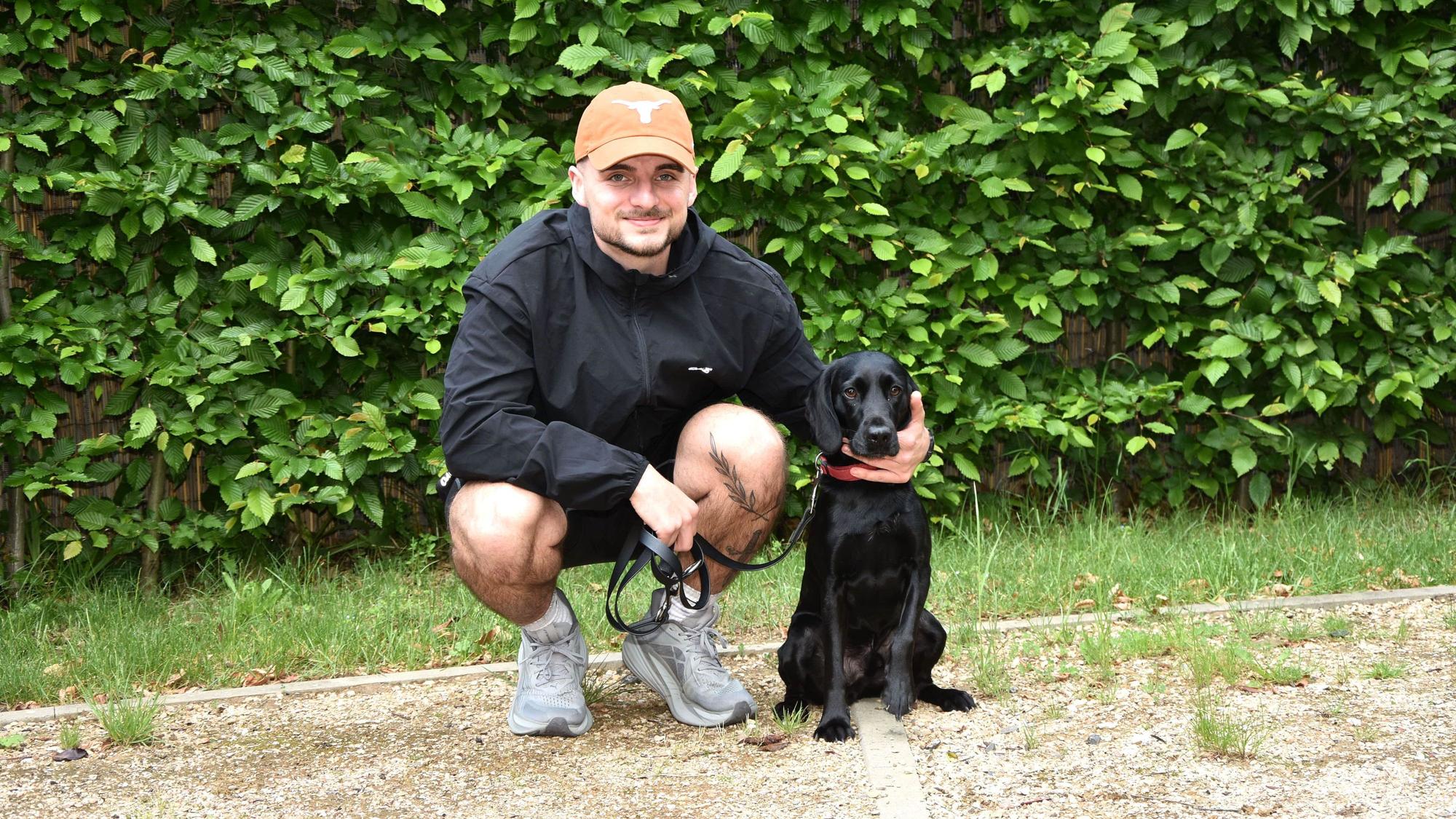 Das Foto zeigt einen Mann mit einem schwarzen Hund.