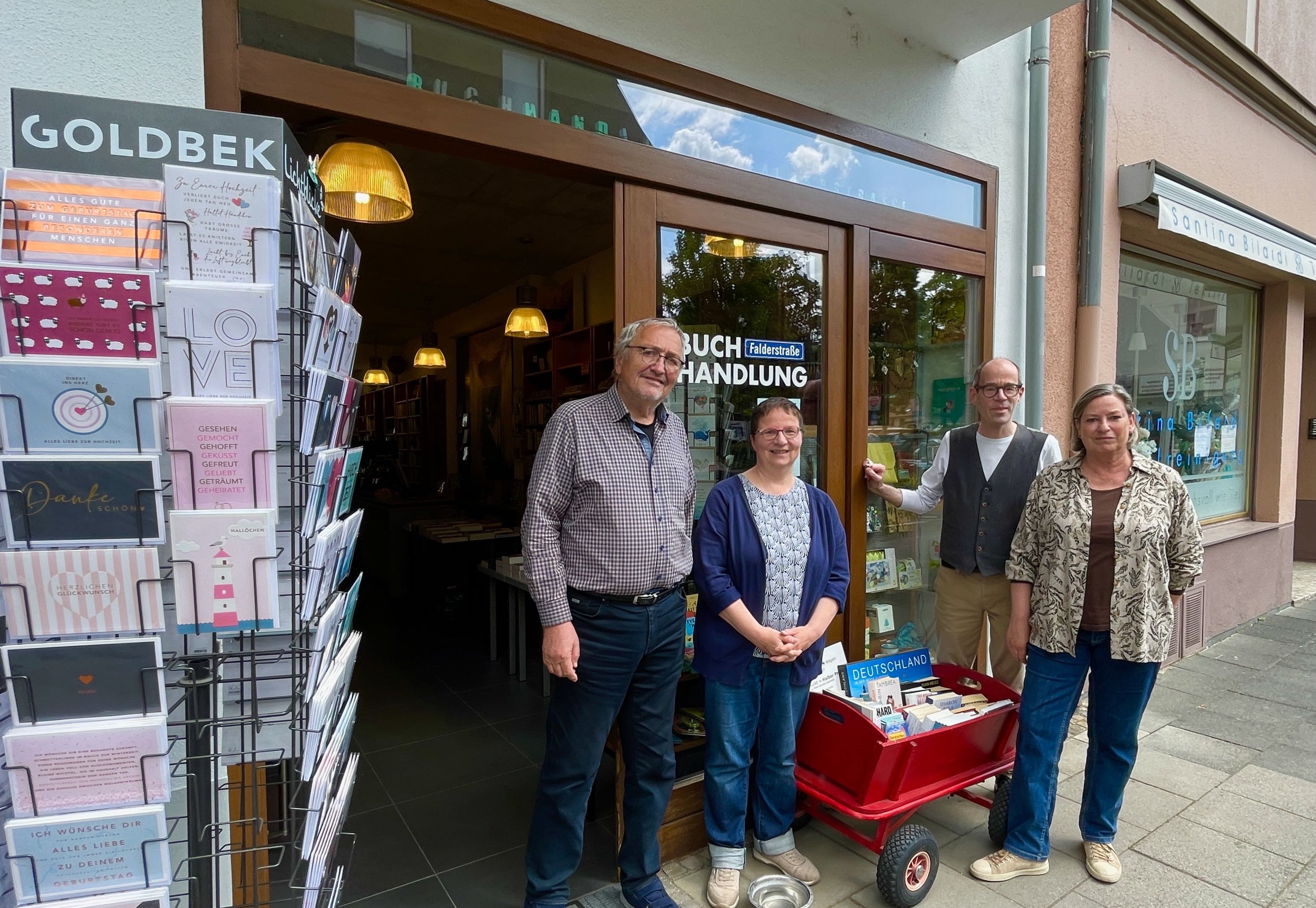 Zwei Männer und zwei Frauen stehen vor dem Schaufenster eines Buchladens.
