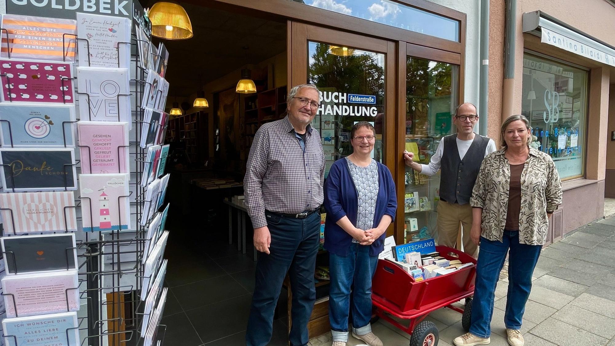 Zwei Männer und zwei Frauen stehen vor dem Schaufenster eines Buchladens.