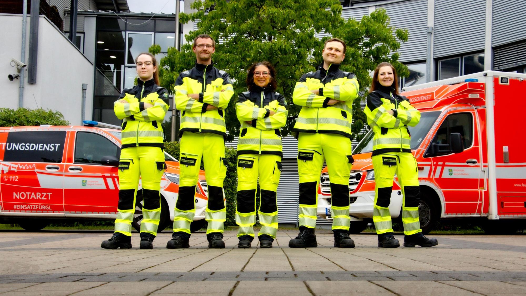 Rettungsdienstmitarbeitende stehen vor Einsatzfahrzeugen der Feuerwehr Bergisch Gladbach.