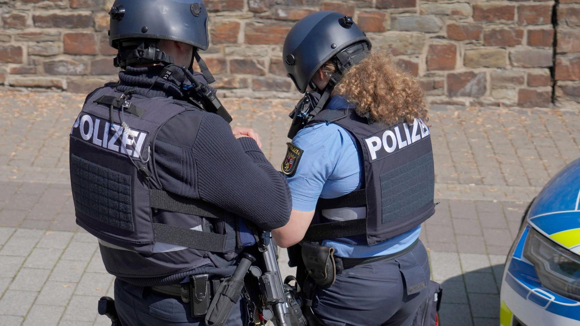 Polizisten stehen in der Nähe der Bankfiliale, ausgerüstet mit Helmen und schusssicheren Westen.
