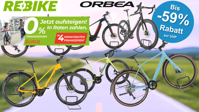 Sechs refurbished Orbea-Fahrräder und E-Bikes unterschiedlicher Kategorien – darunter ein E-Mountainbike, ein Trekking-E-Bike, ein Gravelbike und ein City-Bike – vor einem unscharfen Straßen- und Landschaftshintergrund. Im Bild die Logos von Rebike und Orbea.
